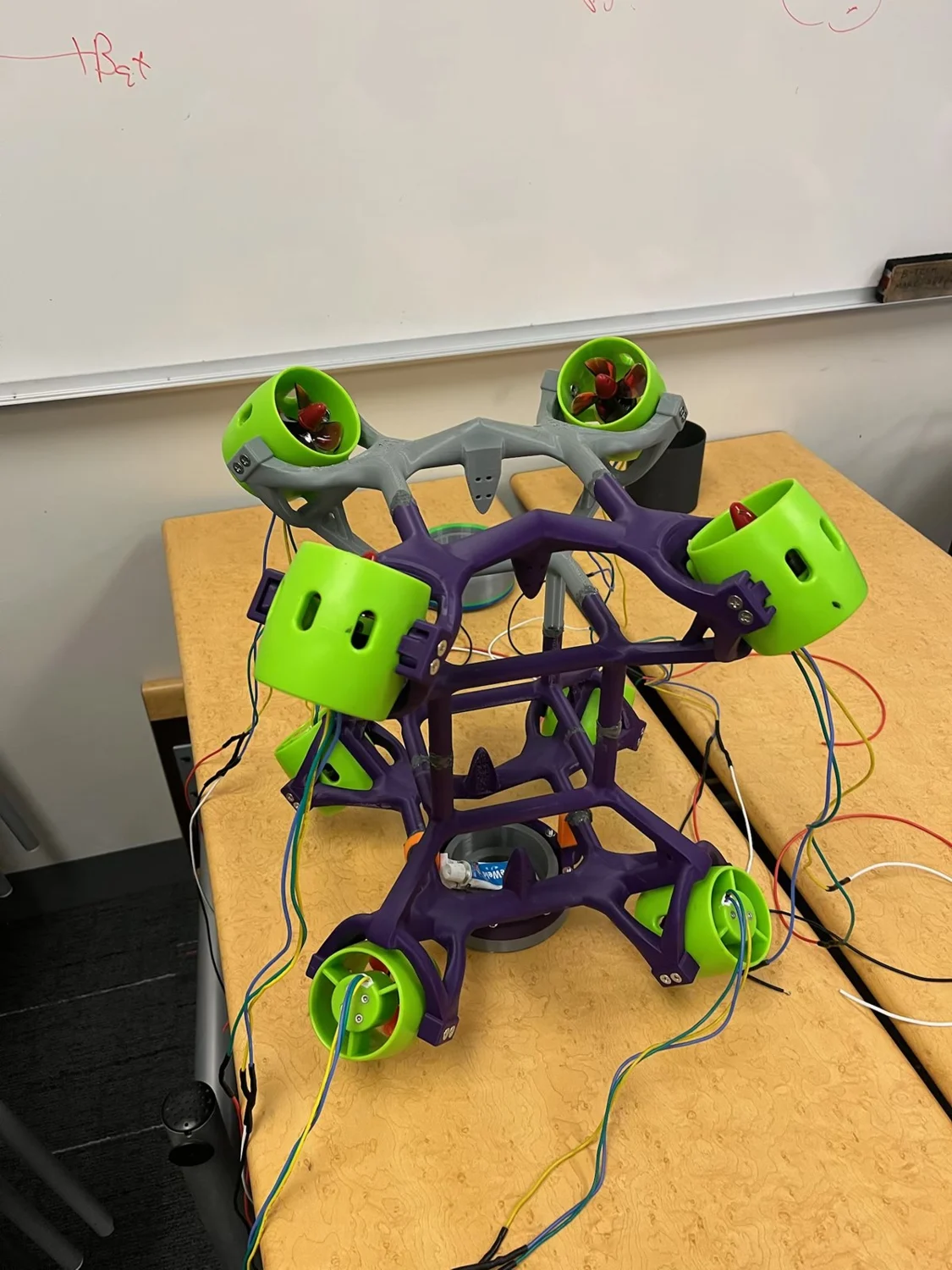 N3M0 prototype with eight green thrusters and a purple printed frame on the workshop bench